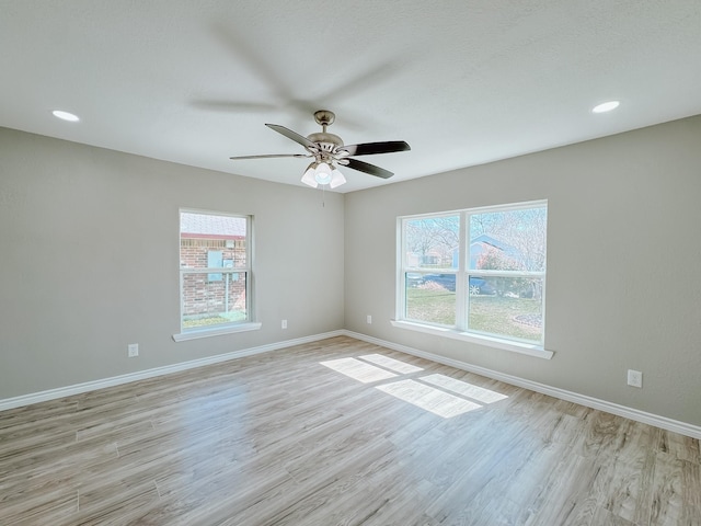 spare room with a wealth of natural light, baseboards, and light wood-style flooring