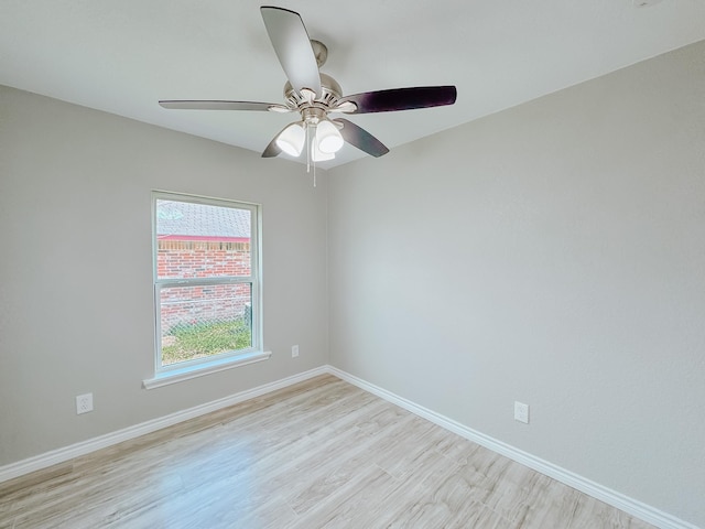 spare room with a ceiling fan, light wood-type flooring, and baseboards