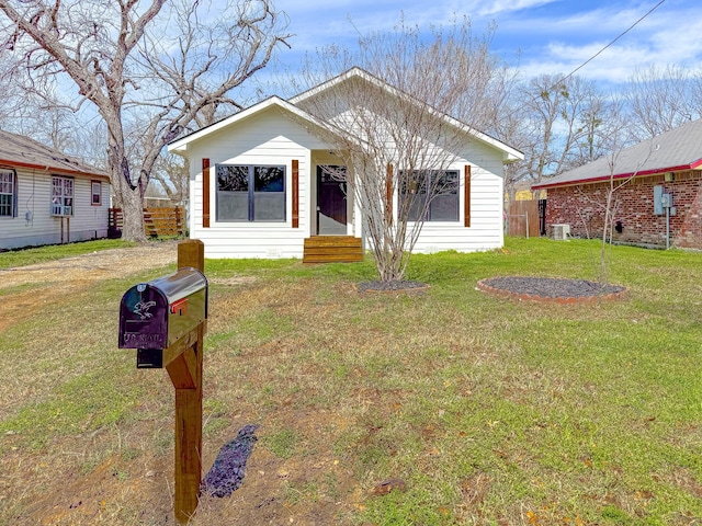 bungalow-style home featuring central air condition unit, a front lawn, and fence