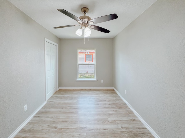 unfurnished room featuring light wood-type flooring, baseboards, and a textured wall