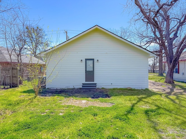 rear view of property featuring a yard, fence, and entry steps