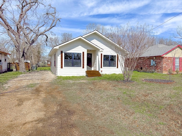 bungalow featuring a front yard and dirt driveway