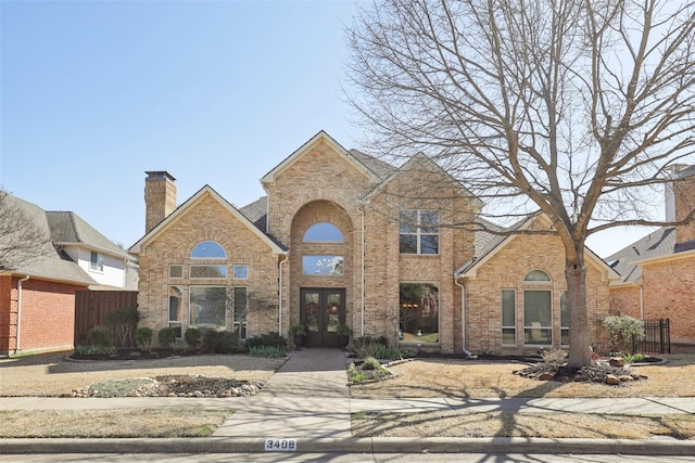 traditional-style home with french doors, brick siding, and fence