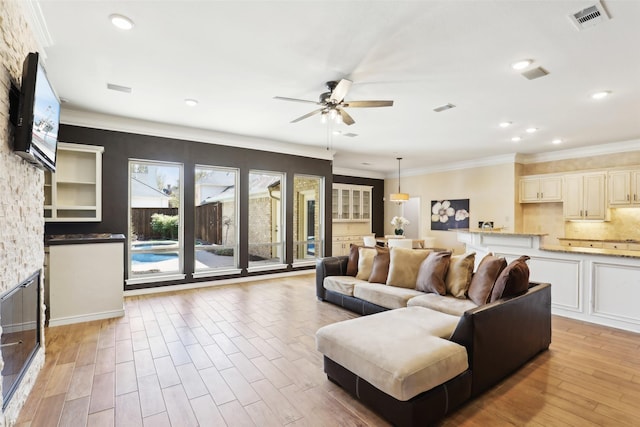 living area with a ceiling fan, light wood-style floors, and crown molding