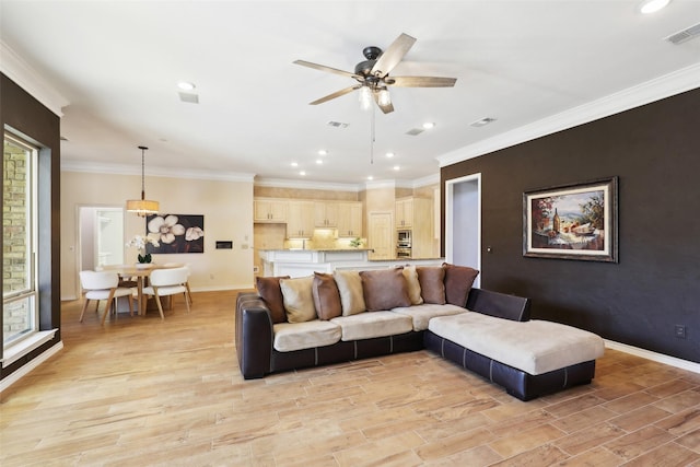 living area with visible vents, crown molding, baseboards, light wood-type flooring, and a ceiling fan