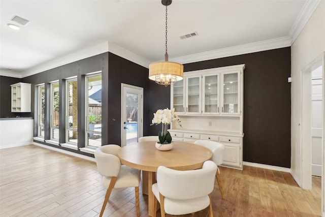 dining space with visible vents, light wood-style flooring, crown molding, and an inviting chandelier