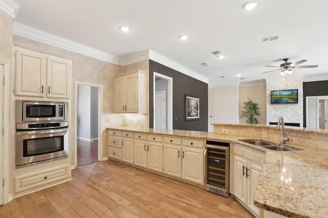 kitchen with visible vents, beverage cooler, a sink, light stone counters, and stainless steel appliances