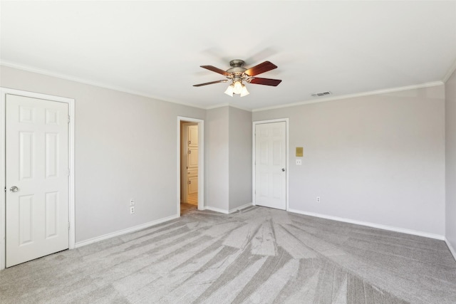 carpeted empty room featuring crown molding, baseboards, visible vents, and ceiling fan