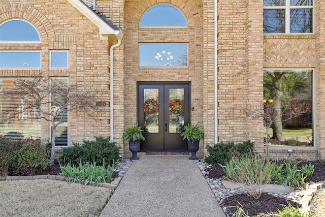 entrance to property featuring french doors and brick siding