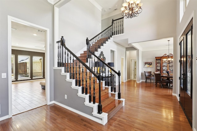 interior space with ornamental molding, a high ceiling, baseboards, and hardwood / wood-style floors