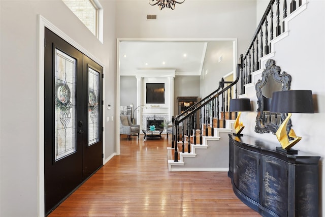 entrance foyer featuring visible vents, a fireplace, stairs, hardwood / wood-style flooring, and french doors