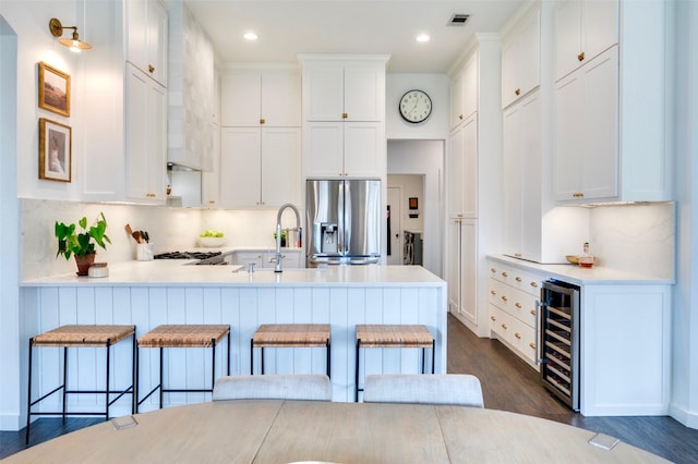 kitchen featuring dark wood-style floors, a peninsula, stainless steel fridge with ice dispenser, a sink, and wine cooler