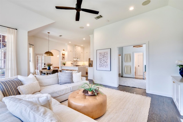 living room with dark wood-style floors, visible vents, recessed lighting, and lofted ceiling