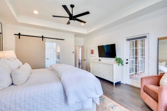 bedroom featuring wood finished floors, a barn door, crown molding, a raised ceiling, and access to exterior