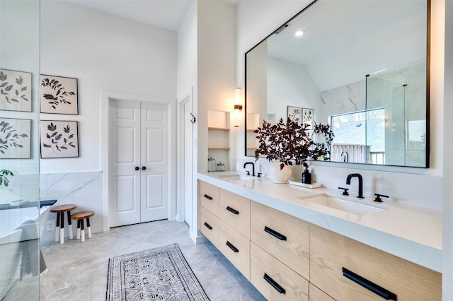 full bath with a sink, lofted ceiling, marble finish floor, and double vanity