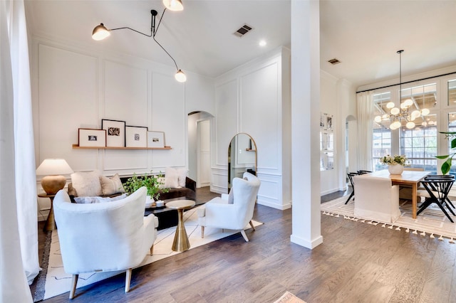 living room featuring visible vents, arched walkways, wood finished floors, and a decorative wall