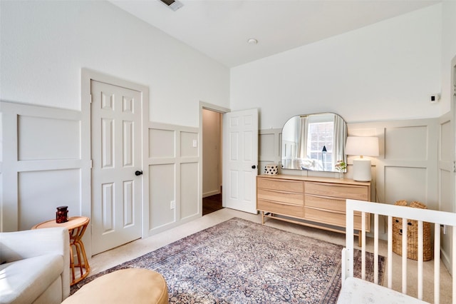 bedroom featuring a decorative wall and wainscoting