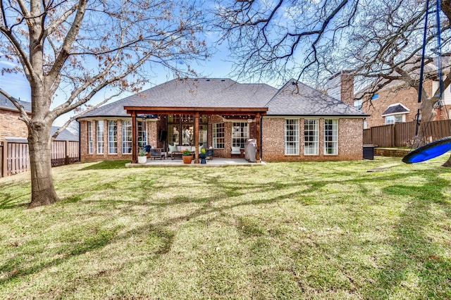 rear view of property with a patio, a fenced backyard, a chimney, a lawn, and brick siding