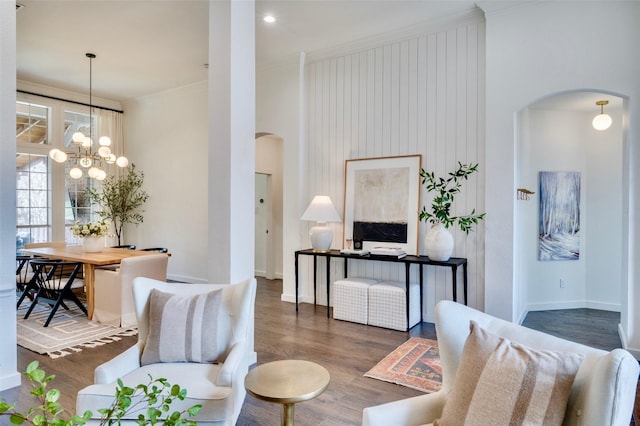 living area featuring wood finished floors, arched walkways, a high ceiling, crown molding, and baseboards