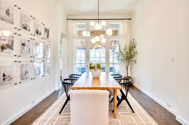 dining room with a chandelier, crown molding, baseboards, and wood finished floors