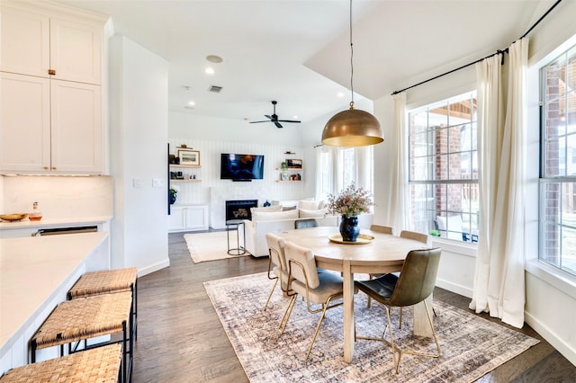 dining area with dark wood-type flooring, a fireplace, visible vents, and a healthy amount of sunlight