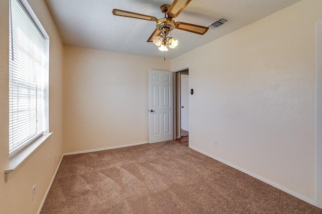 empty room featuring baseboards, visible vents, a textured ceiling, and carpet