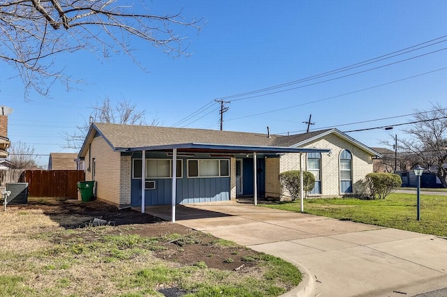 view of front of house with driveway, central AC, fence, a front yard, and brick siding