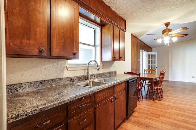 kitchen with a sink, a textured ceiling, light wood finished floors, dishwashing machine, and ceiling fan