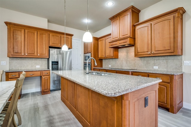 kitchen with a sink, custom exhaust hood, appliances with stainless steel finishes, and brown cabinetry