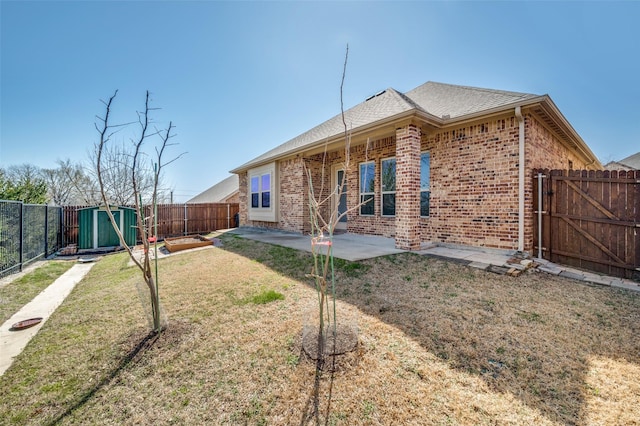 back of house featuring a storage shed, an outbuilding, a fenced backyard, and brick siding