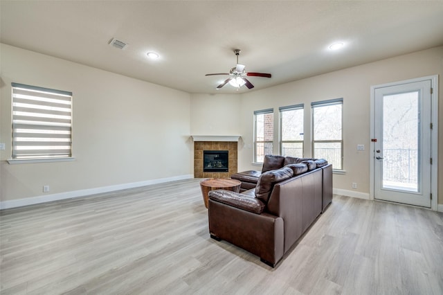 living area with visible vents, a fireplace, baseboards, and light wood-style floors