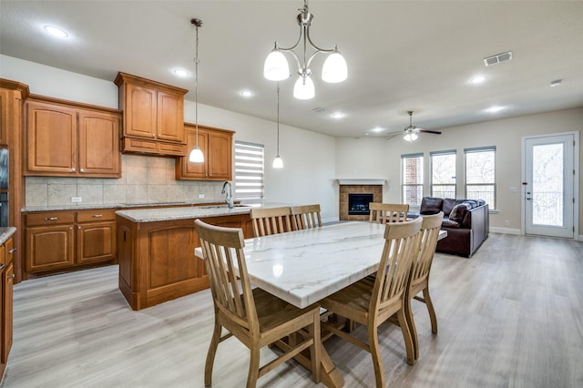 dining room with a ceiling fan, visible vents, light wood finished floors, recessed lighting, and a tiled fireplace