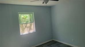 spare room with ceiling fan, baseboards, and dark wood finished floors