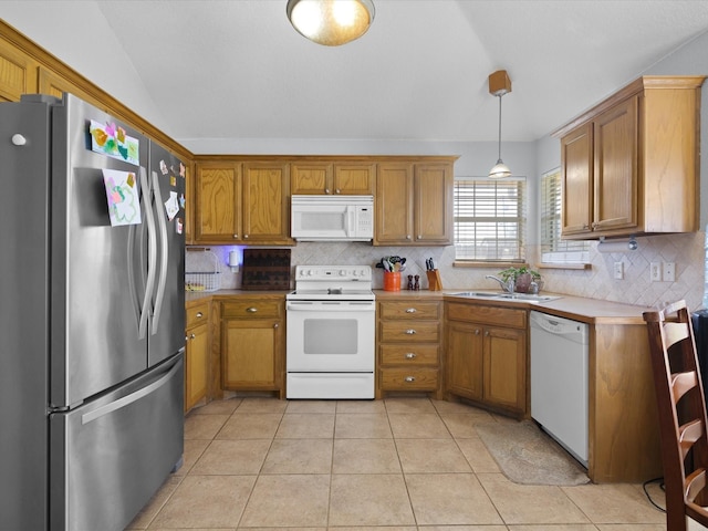 kitchen featuring brown cabinetry, backsplash, white appliances, and a sink