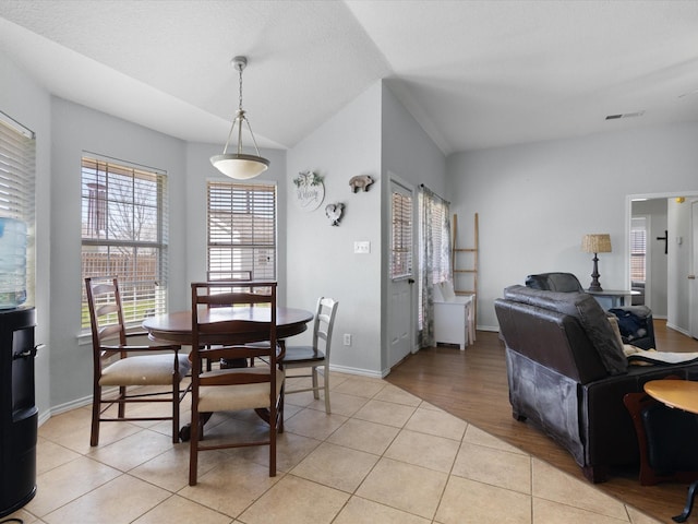 dining space with vaulted ceiling, light tile patterned flooring, visible vents, and baseboards