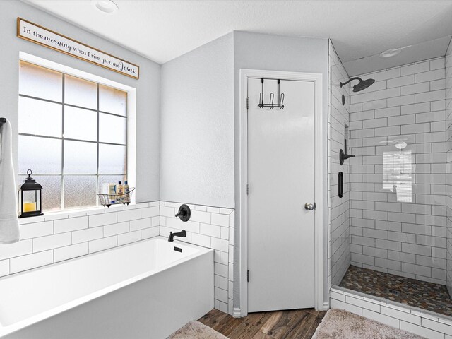 bathroom featuring a shower stall, a garden tub, and wood finished floors