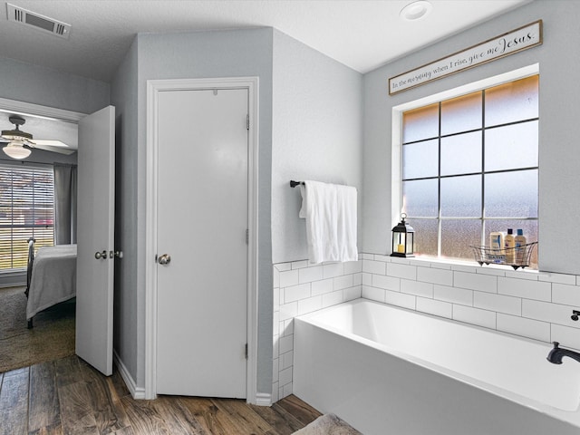 bathroom featuring connected bathroom, visible vents, wood finished floors, and a bath