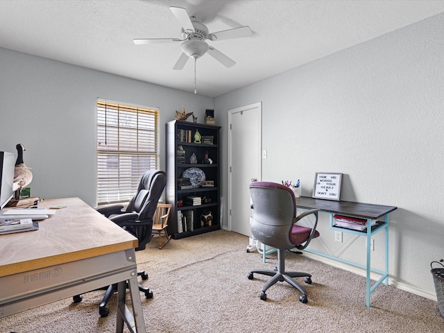 carpeted office featuring a ceiling fan, a textured wall, and a textured ceiling