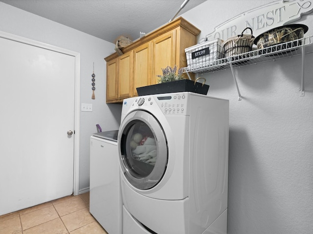 laundry area with cabinet space, a textured ceiling, washing machine and dryer, and light tile patterned flooring