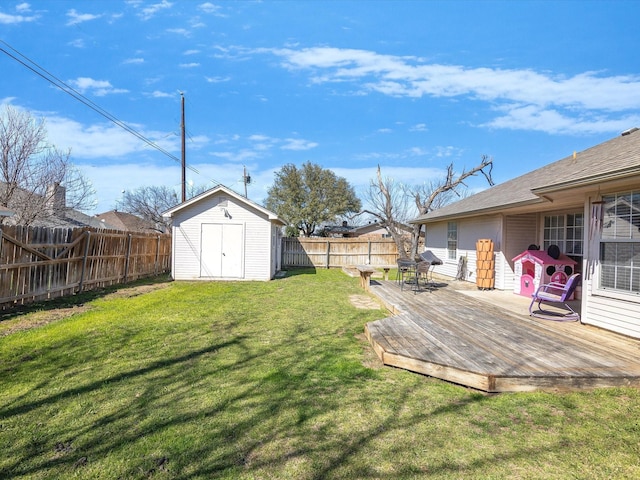 view of yard featuring an outbuilding, a wooden deck, a storage shed, and a fenced backyard