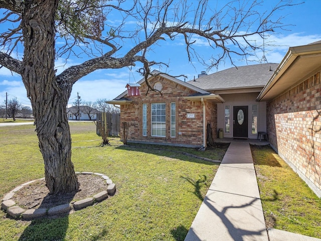 doorway to property with brick siding, a lawn, and a shingled roof