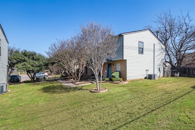 view of property exterior with brick siding, a yard, central AC, and fence