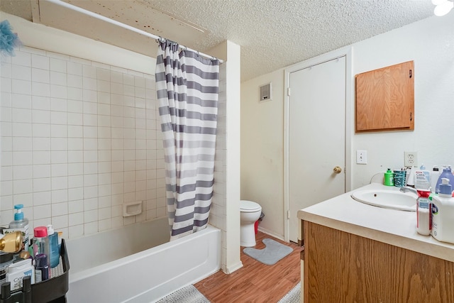 bathroom featuring vanity, wood finished floors, shower / tub combo, a textured ceiling, and toilet