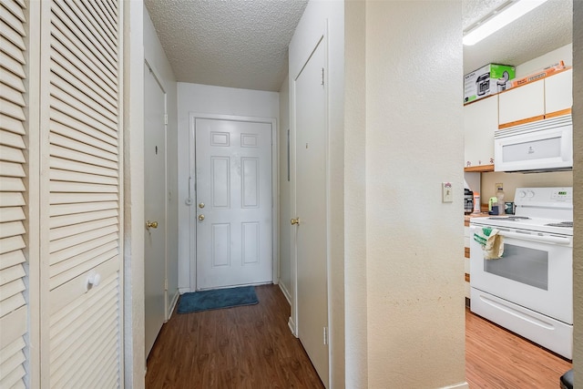 hall with a textured ceiling and wood finished floors