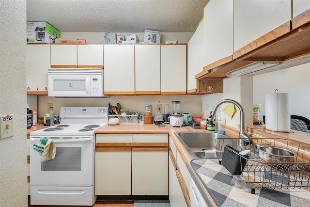 kitchen with white appliances, white cabinets, light countertops, and a textured ceiling