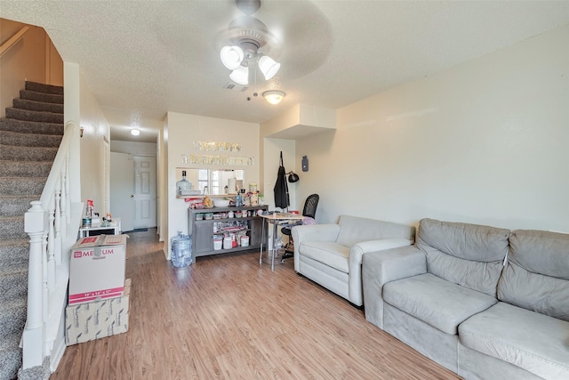 living area featuring stairs, light wood-style flooring, visible vents, and a textured ceiling