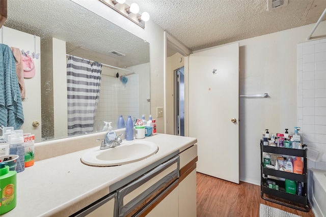 bathroom featuring visible vents, a shower with curtain, wood finished floors, and a textured ceiling