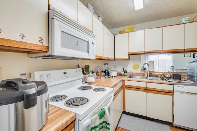 kitchen featuring a sink, a textured ceiling, white cabinetry, white appliances, and light countertops