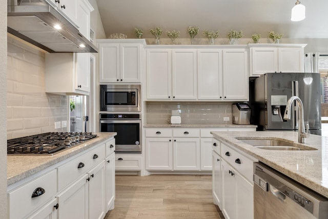 kitchen with a sink, stainless steel appliances, white cabinets, light wood-style floors, and under cabinet range hood