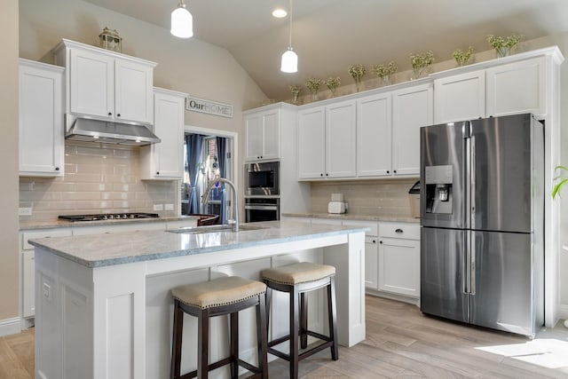 kitchen featuring under cabinet range hood, a sink, appliances with stainless steel finishes, white cabinets, and lofted ceiling